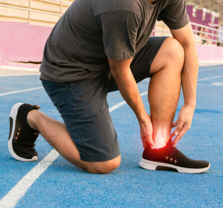 Person holding their painful ankle on a sports court.